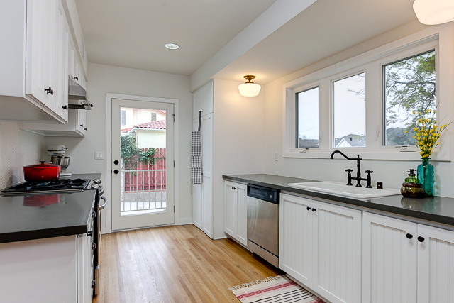 Galley kitchen with stainless steel appliances, quartz counters and hex tile backsplash