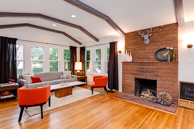 Living room with original wood floors, beamed/barreled ceiling and brick fireplace